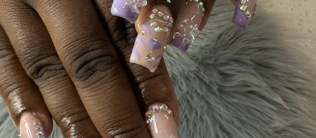 A row of decorated lilac nails with crystal accents.