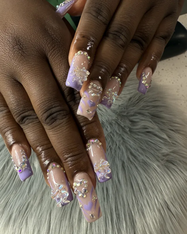 Lilac coffin nails with rhinestones and 3D bows on a soft backdrop.